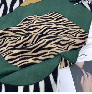 Detail view of a cozy cashmere-feel zebra print scarf with tassels for autumn and winter.