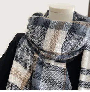 Detail view of winter plaid cashmere-feel scarf, soft texture, cozy grey and brown tones.