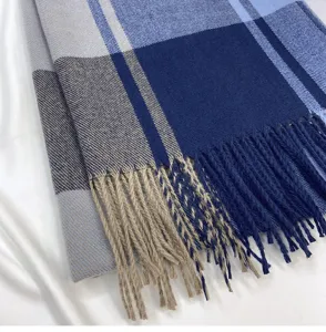 Detailed close-up of blue and grey plaid fringed scarf, soft warm winter fabric accessory.