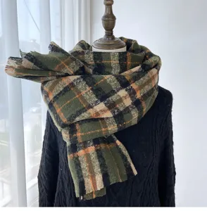 Detail view of a retro green and black plaid winter cashmere-feel scarf with fringe edges.