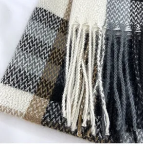 Close-up detail of soft imitation cashmere plaid scarf with elegant tassels, cozy texture.