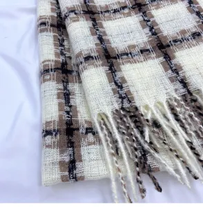 Close-up detail shot of a classic black brown and white plaid winter warm tassel scarf.