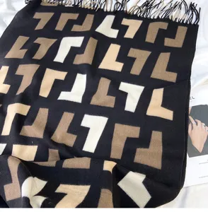 Detailed view of women autumn winter cashmere feel scarf with tassel and luxury monogram pattern.
