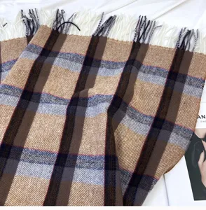 Gros plan d'une écharpe d'hiver douillette à motif écossais classique et franges douces.