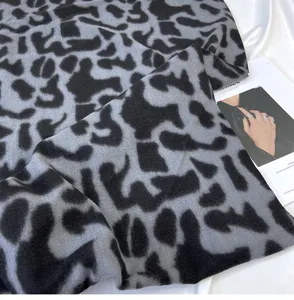 Detail view of the soft imitation cashmere scarf featuring a chic black and grey leopard pattern.