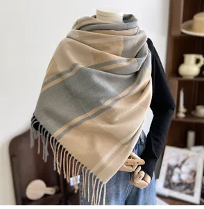 Detailed view of the cozy plaid cashmere-feel scarf with elegant tassels in neutral tones.