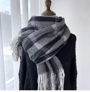 Gros plan détaillé de l'écharpe d'hiver à carreaux gris avec de douces franges sur mannequin.