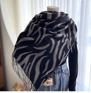 Zebra striped tassel scarf detail showing soft cashmere feel texture and elegant fringe design.