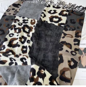 Close-up detail of cozy leopard print patchwork winter scarf with elegant tassels.
