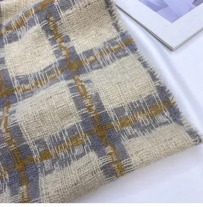 Close-up detail of soft plaid scarf fabric featuring beige, grey and yellow checkered pattern.