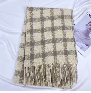 Detailed view of winter plaid scarf with tassels, beige grey check pattern fabric close up.