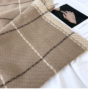 Close-up detail of soft winter plaid cashmere-feel scarf in classic beige brown pattern.