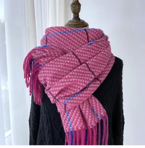 Close-up detail of the pink knitted plaid scarf showing soft texture and fringe design.