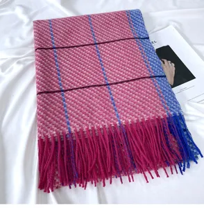 Detailed close-up view of the pink and blue plaid winter scarf featuring soft fringe trim.