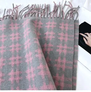 Detailed close-up of grey and pink grid cashmere-feel scarf with fringe. Soft winter texture.