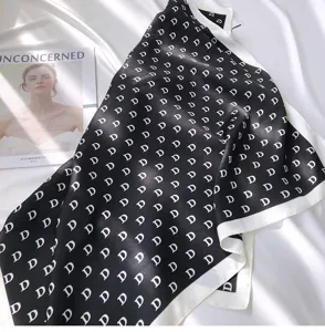 Detailed view of black and white silk scarf with repeating letter pattern, elegant fashion accessory.