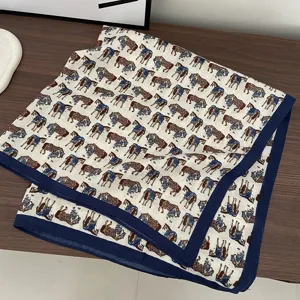 Detailed view of a retro horse print square scarf with navy blue border on wooden table.