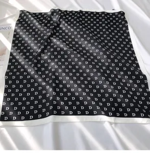 Detailed shot of black and white square silk scarf with classic letter D monogram pattern.