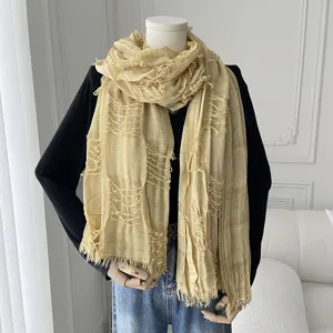 Detailed view of the stylish beige distressed gauze scarf draped on mannequin, ideal for spring.