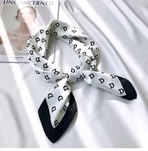 Detailed view of women silk scarf with black monogram letter D print and elegant contrast tips.