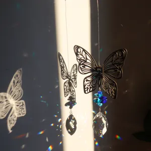 Dettaglio di un acchiappasole a farfalla in metallo con cristalli e riflessi arcobaleno.