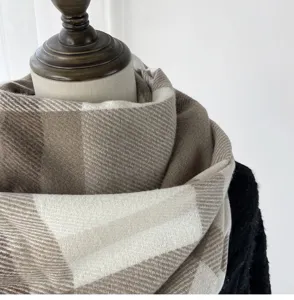 Close-up detail of the soft winter plaid scarf in beige and white cashmere-like fabric.