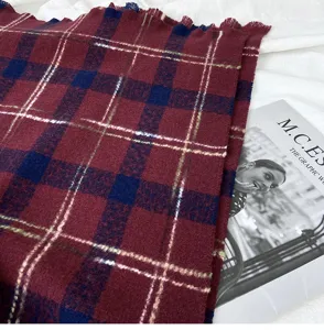 Cozy winter plaid scarf detail, soft woolen fabric texture and chic fringe edge for cold days.