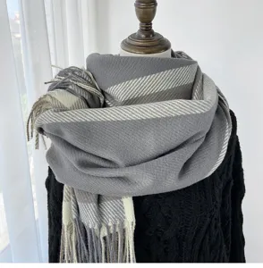 Detailed view of grey and beige plaid winter scarf with cozy fringe tassels on mannequin display.