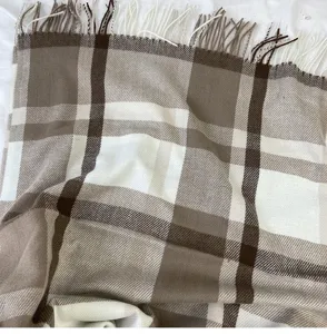 Close-up detail view of soft brown and white plaid pattern tassel blanket scarf.