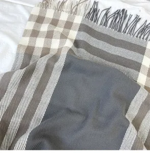 Detail shot of winter women tassel plaid scarf showcasing soft cashmere-feel fabric and texture.