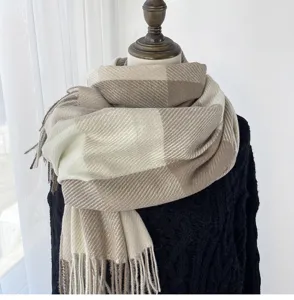 Detailed view of cozy beige and white plaid winter scarf with elegant fringe trim design.