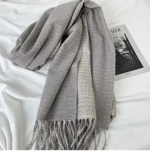 Grey cashmere-like winter scarf detail showcasing soft woven texture and elegant fringe edges.