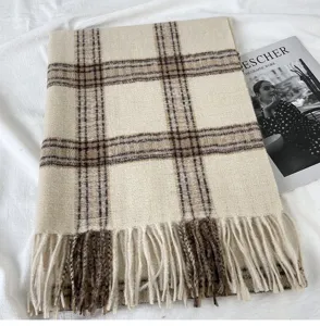 Close up detail view of the thick warm plaid tassel winter scarf in stylish beige and brown.
