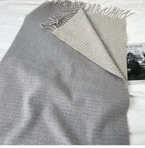 Detailed view of the dual-sided reversible grey and beige fringe scarf, showcasing soft texture.