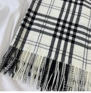 Detailed view of classic black and white plaid winter scarf featuring cozy fringe tassels.
