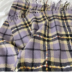 Detailed closeup of a cozy purple plaid winter scarf with fringe, soft cashmere-feel fabric.