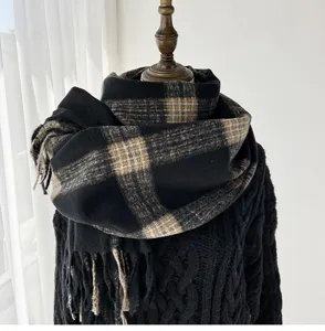 Detailed view of a thick cozy plaid winter scarf in black and brown with elegant fringe.