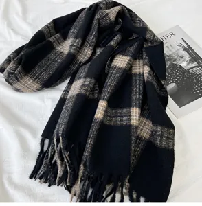 Close-up detail of the cozy black and brown plaid winter scarf with elegant fringe tassels.