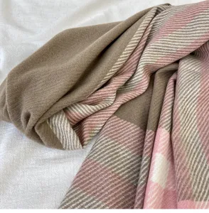 Close-up of a stylish winter plaid cashmere-feel scarf, soft brown and pink textured fabric.