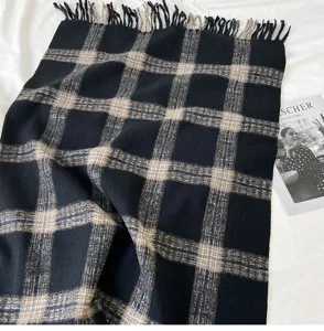 Detailed close-up shot of classic black and beige plaid scarf with soft cozy fringe.