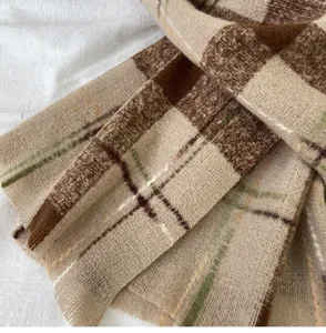 Close-up detail of cozy winter plaid scarf texture, retro brown and beige check pattern.