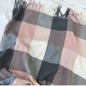 Close-up detail of cozy pink and gray plaid winter scarf with fringe, soft texture.