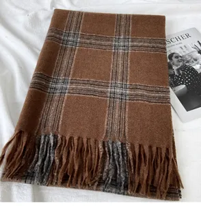 Detail view of a brown plaid winter scarf with cozy fringe tassels and soft textured fabric.