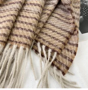 Close-up detail of cozy brown striped winter scarf with soft fringe texture and warm tone.