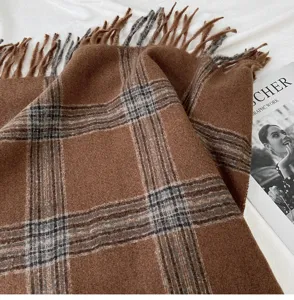 Close-up detail of cozy brown plaid winter scarf texture with elegant fringes style.