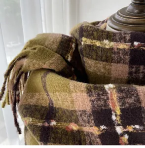Close-up detail of soft autumn winter plaid scarf fabric texture and fringe design.