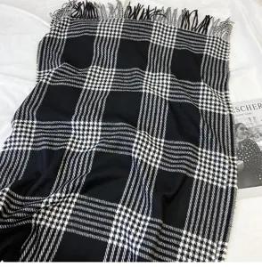 Schwarz-weißer Karoschal für den Winter mit klassischem Fransenmuster, warm und gemütlich.