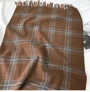 Detailed close-up of brown plaid scarf with tassels, soft knitted texture and warm winter pattern.