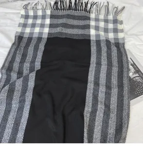 Detailed view of black grey plaid scarf featuring soft fabric and classic fringe trim.