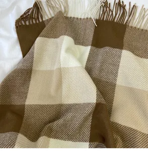 Close-up detail of cozy brown and white plaid scarf with fringe, soft winter accessory.